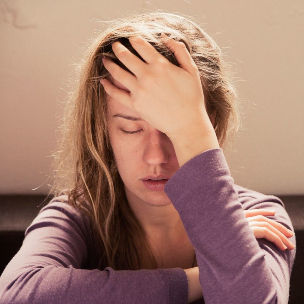 Woman suffering from stress or a headache grimacing in pain stock photo