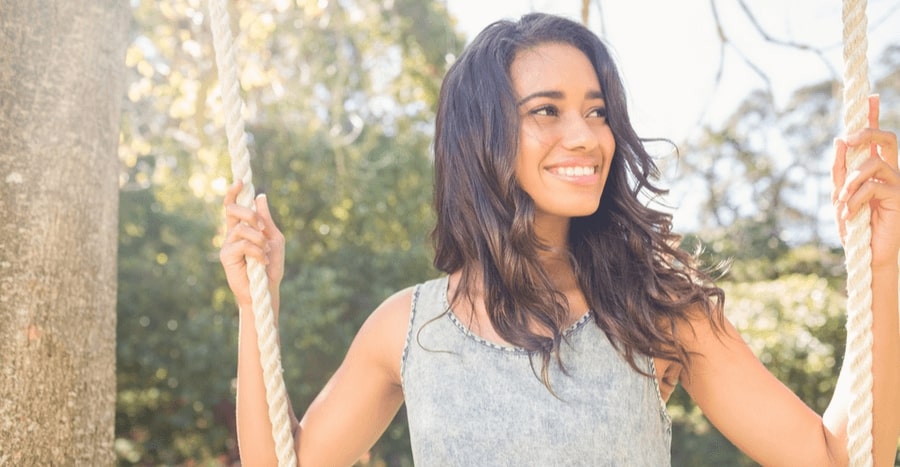 Woman enjoying a swing in a sunny outdoor setting.