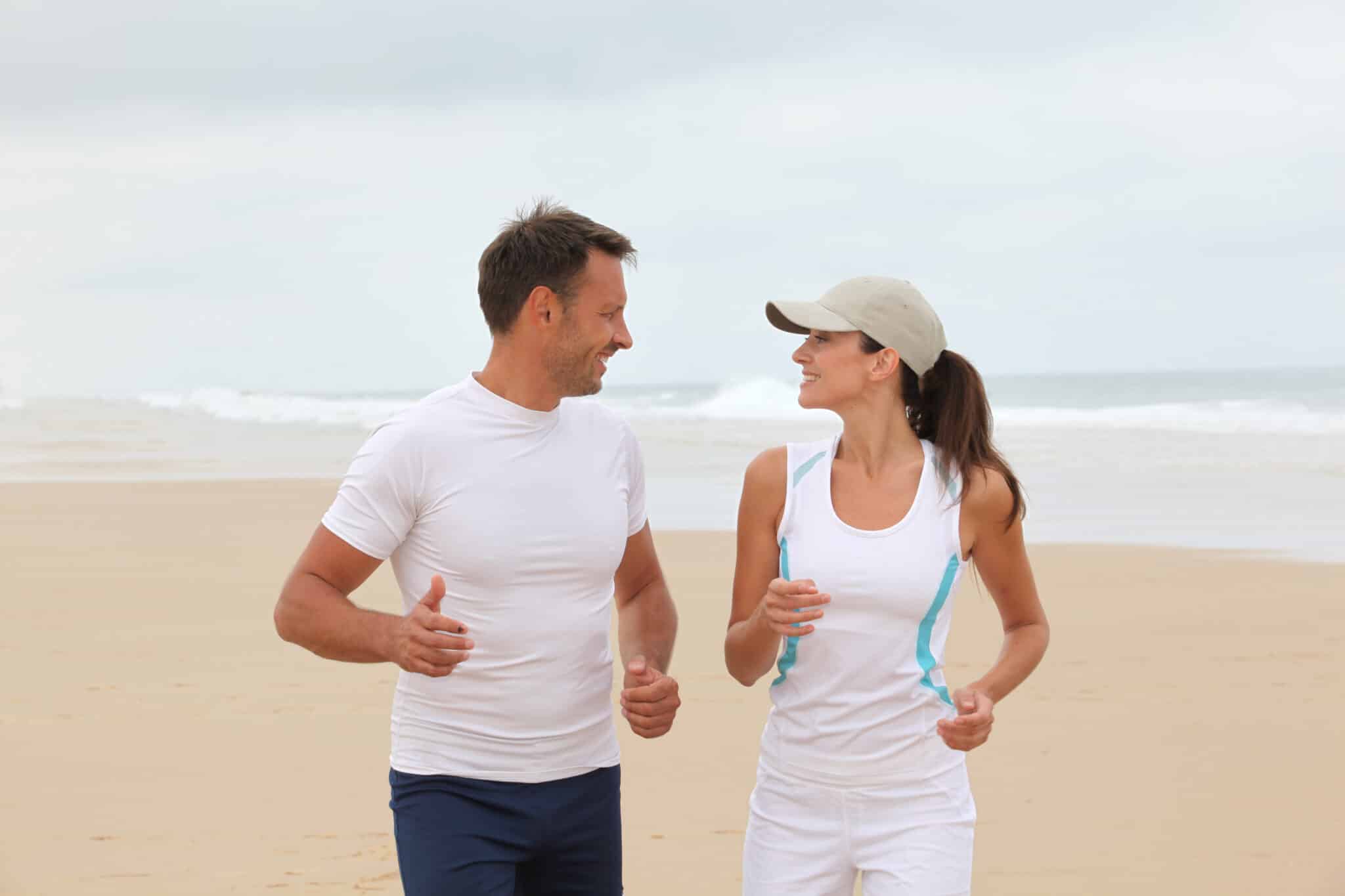 Couple jogging on a beach, related to hormone therapy benefits.