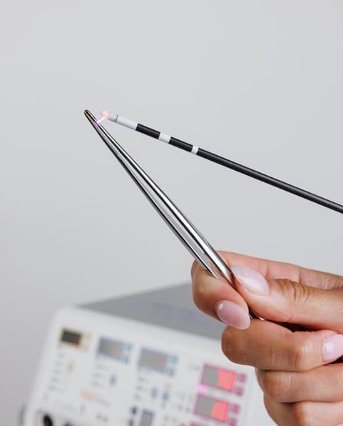 Renuvion device held by a hand, used for skin tightening.